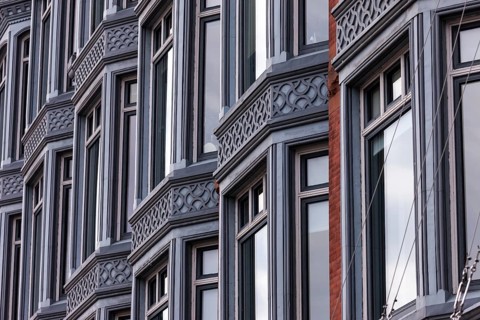 Facade of a building with a series of windows and intricate architectural designs, reflecting a