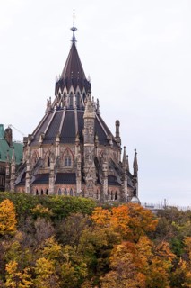 The Canadian Parliament Buildings with spires surrounded by colorful autumn trees in Ottawa,