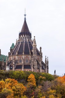 The stately Canadian Parliament Buildings with their Gothic structure with a tall spire and autumn