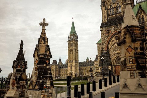 View of the Canadian parliament building from the foreground of stone monuments, featuring gothic