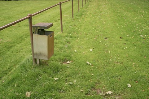 Borken, NRW, Germany, Empty metal garbage bin standing next to a railing in a public park with