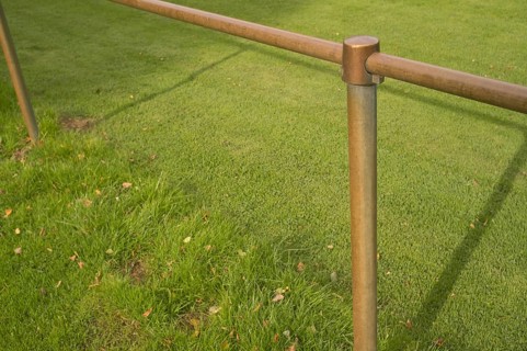 Borken, NRW, Germany, Bronze colored metal railing creating a barrier in a park with lush green