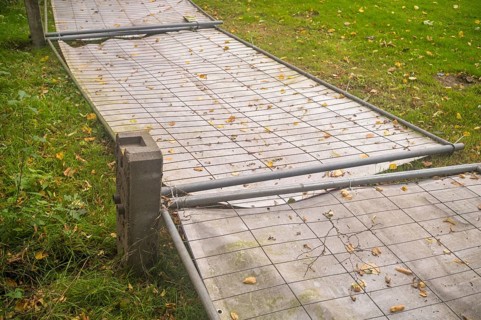 Borken, NRW, Germany, Temporary metal fence panels lying on the ground surrounded by green grass