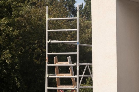 Borken, NRW, Germany, Scaffolding frame with wooden ladder against a building exterior and green