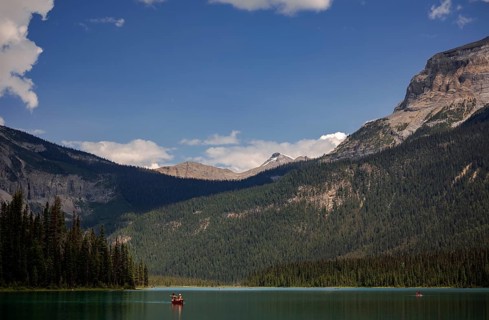 Canoe on a serene Emerald Lake surrounded by the Canadian Rocky Mountains under a blue sky with