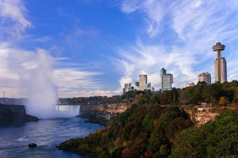 Skyline with prominent tower and the Horseshoe Falls under a bright blue sky in Niagara Falls,
