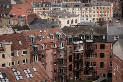 Cityscape featuring residential buildings with red tile roofs under an overcast sky in Aarhus,