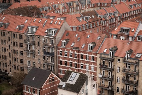 Urban scene showcasing densely packed buildings with red tile roofs on a cloudy day in Aarhus,