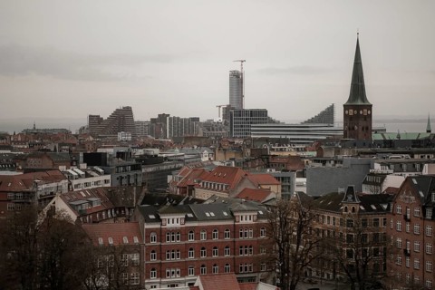 Urban skyline with historic and modern buildings under a gray sky, featuring several towers in