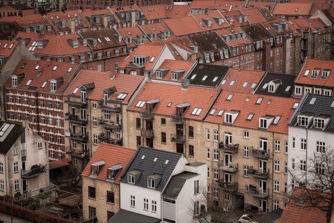 View of a residential area with red-tiled rooftops and brick buildings under a cloudy sky in