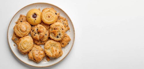 A top-down shot showcases a variety of golden-brown cookies arranged on a speckled plate against a