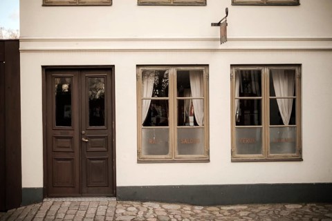A vintage building facade with wooden doors and windows, featuring cobblestone pavement in