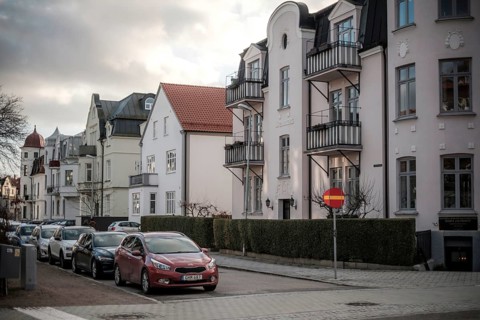 Street view of European residential buildings with parked cars and a cloudy sky in Helsingborg,