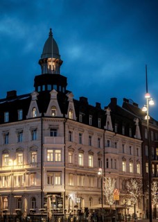 An elegant historic building with illuminated windows against a blue evening sky in Helsingborg,