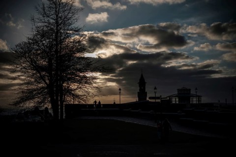 Silhouette of figures and a tower at sunset with a dramatic cloud-filled sky in Helsingborg,