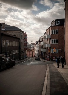 Steep street flanked by residential buildings under a dramatic cloudy sky in Helsingborg, Sweden,
