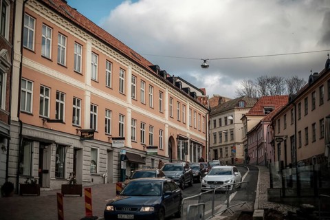 City street with parked cars and pastel-colored buildings under a cloudy sky in Helsingborg,