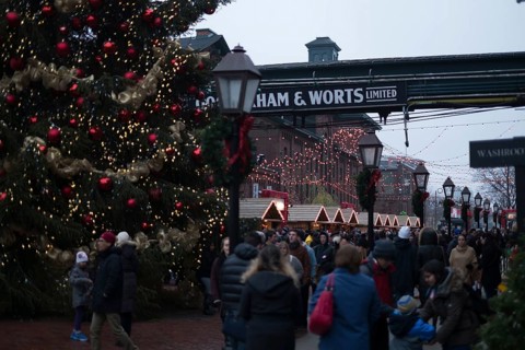 A bustling outdoor Christmas market at the Gooderham and Worts Distillery District, with festive