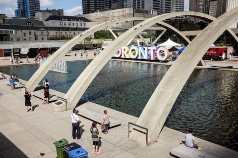 Public plaza in Toronto with arches over a fountain and people enjoying the sunny day in Toronto,