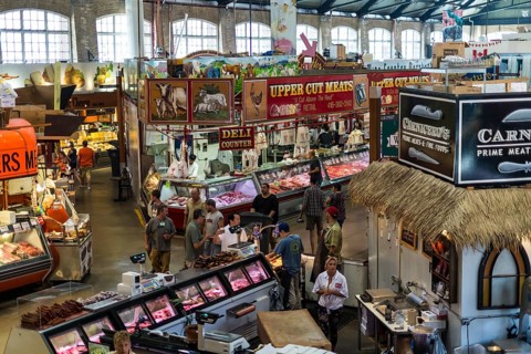 A bustling indoor market at St. Lawrence Market, with meat vendors and colorful displays in