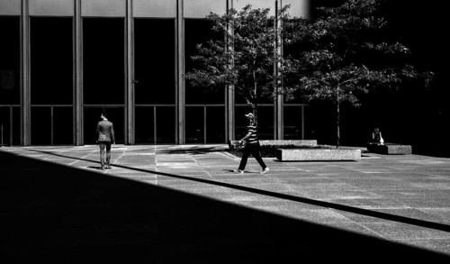 People walking in a modern urban environment with a balance of light and shadow, creating a dynamic