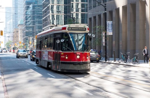 A red streetcar traveling along busy city streets in Toronto, Ontario, Canada, North America