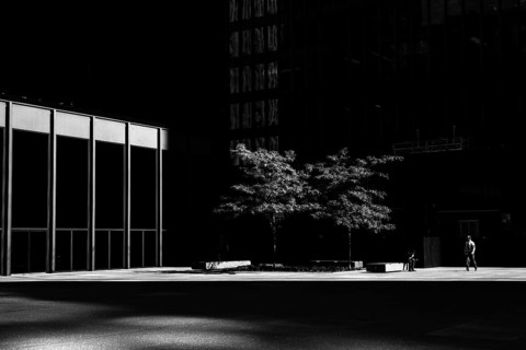 A lone person in a stark urban setting with dramatic light and shadow interplay, emphasizing