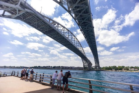 People enjoying the river view underneath the Blue Water Bridge, connecting Canada to the United