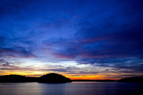 A vivid sunset over a lake, displaying a colorful horizon at twilight in Muskoka, Ontario, Canada,