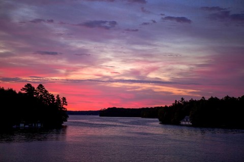 A peaceful sunset paints the sky in vibrant colors over a calm lake in Muskoka, Ontario, Canada,