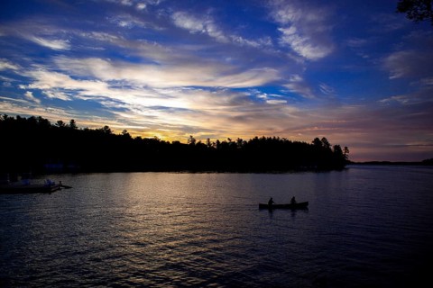 Silhouettes of two canoes on a lake at sunset, creating a peaceful landscape in Muskoka, Ontario,