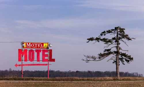 A motel sign and lone tree stand against the sky near Strathroy, Ontario, Canada, North America