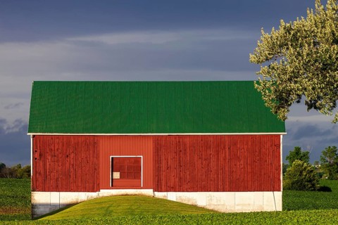 A red barn with a green roof against a cloudy sky in St. Thomas, Ontario, Canada, North America
