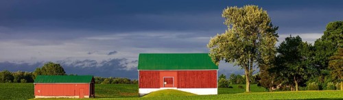A red barn with green roof sits under a dramatic sky in St. Thomas, Ontario, Canada, North America