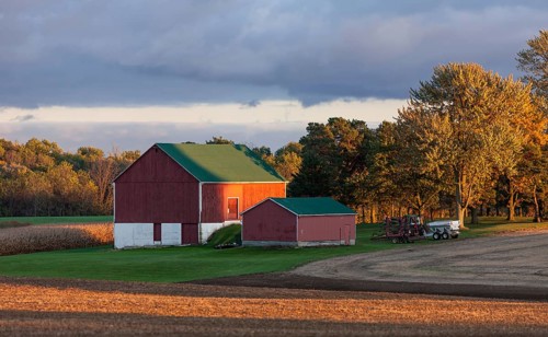 Red barn and fields illuminated by warm sunset in St. Thomas, Ontario, Canada, North America
