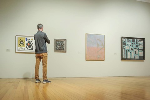 Jan 13, 2024 - Lisbon, Portugal: visitor in gray jacket and tan pants observe abstract artworks
