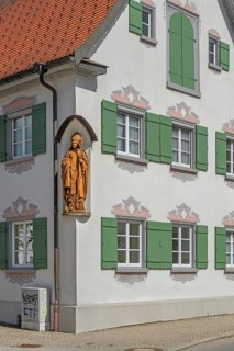 Blue sky, pointed gable house with green shutters and bishop figure, Kisslegg, Allgäu,