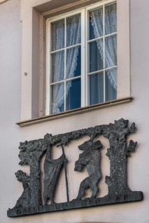 Window with blinds and metal relief, Gallus and the bear on the façade of the pharmacy in Kisslegg,