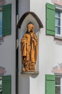 Blue sky, house with green shutters and bishop figure in corner niche, Kisslegg, Allgäu,