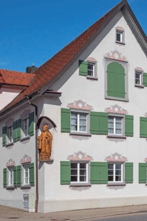 Blue sky, pointed gable house with green shutters and bishop figure, Kisslegg, Allgäu,