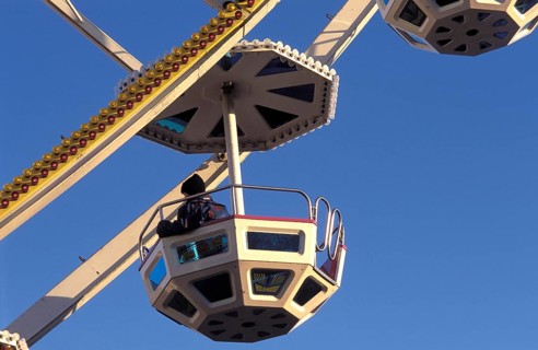 A geometric gondola of a Ferris wheel against a clear blue sky at an amusement park