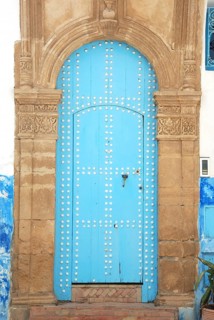 An ancient blue door with an ornate stone archway, featuring a weathered look in a historical