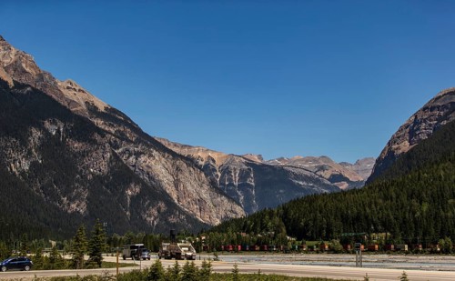 Mountain pass with highway and vehicles, surrounded by forest as viewed from the Trans Canada