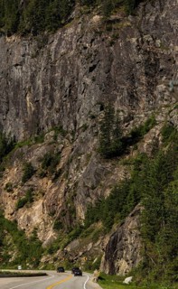Winding road through a rugged mountainous area with dense forest in Revelstoke, British Columbia,