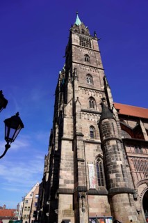 Gothic church tower made of sandstone, rises in front of a bright blue sky, Church of St. Lawrence,