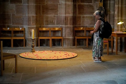 Woman standing in front of lit candles in a church as an expression of devotion, St Lorenz Church,