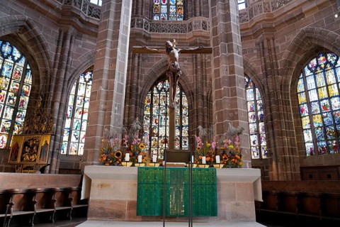 Church altar with cross and colourful stained glass windows depicting biblical scenes, St. Lawrence