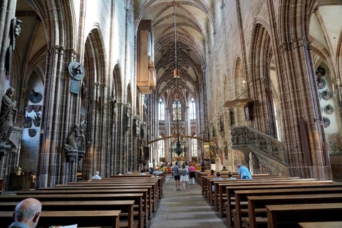 Nave with high vaults, benches and people inside a historic church, Church of St. Lawrence,