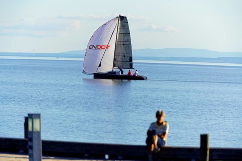 Lake Neusiedl, Burgenland, Austria, Europe, A boy sits on a jetty and watches a catamaran sailing