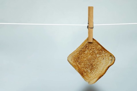 Toasted bread hanging on clothesline with clothespin against white background